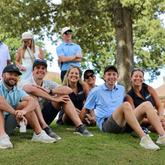 Group of people sitting on grass outdoors with trees in the background
