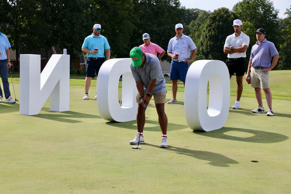 Person playing golf on a green with large white letters spelling 'FENDO' in the background.
