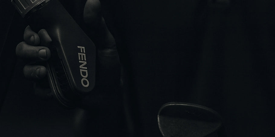 Hand holding a black Fendo against a dark background
