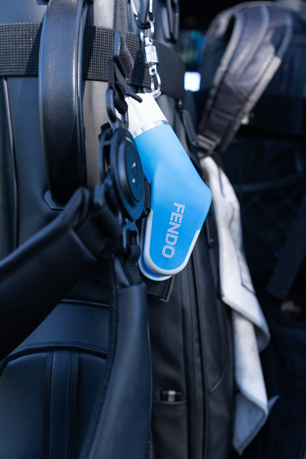 Fendo Club Cleaner clipped to a golf bag, ready for use on the course.